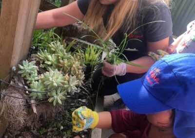 An image of a kid planting new plants with her instructor in childcare carlingford.